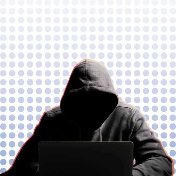 Person in a dark hoodie using a laptop, symbolising online fraud or cybercrime.
